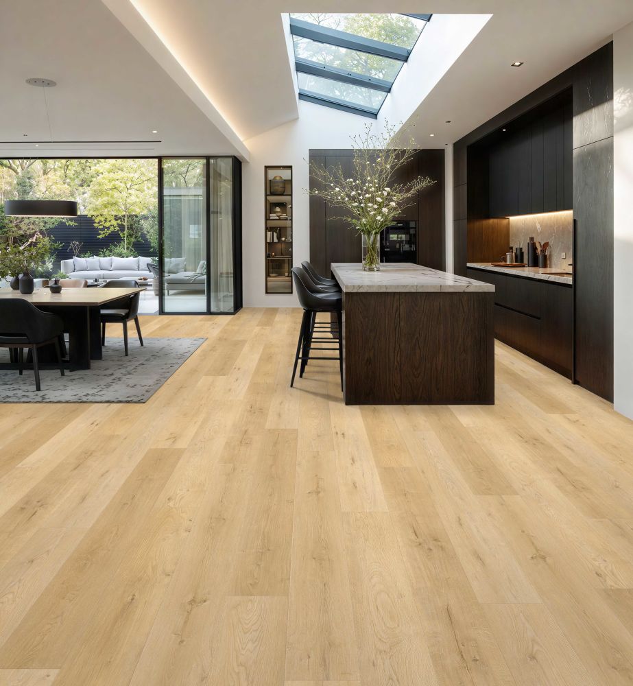 Bright open-plan kitchen with a large central island, dark wood cabinetry, and a skylight flooding the space with natural light; outdoor seating visible through glass doors.