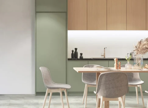 Contemporary kitchen and dining area with a light wood table, four gray upholstered chairs, and green cabinetry along the wall.