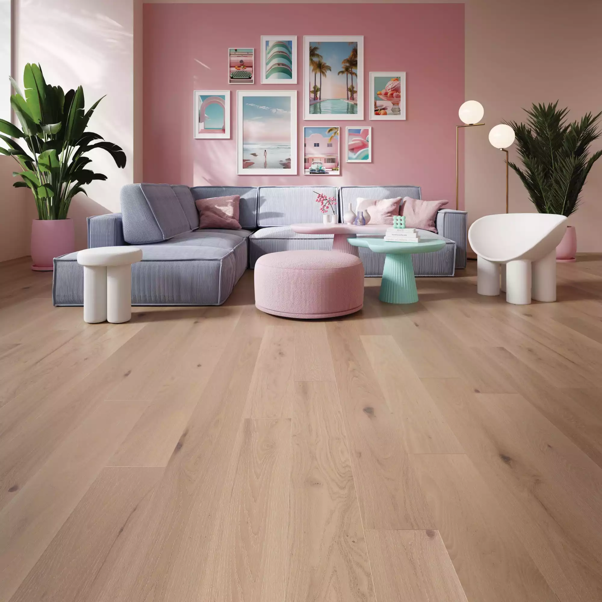 Pastel living room with pink wall, gallery of framed tropical prints above a blue striped sofa and pink pouf. Green plants flank the seating area.